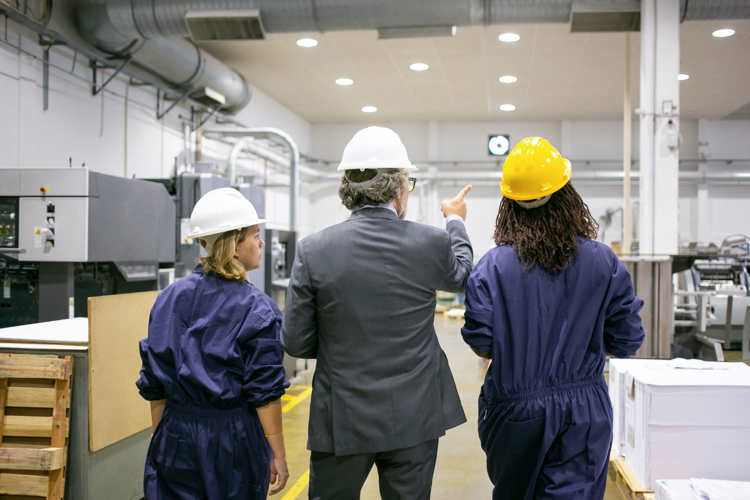 Manager and frontline workers collaborating on the factory floor during a process improvement walkthrough