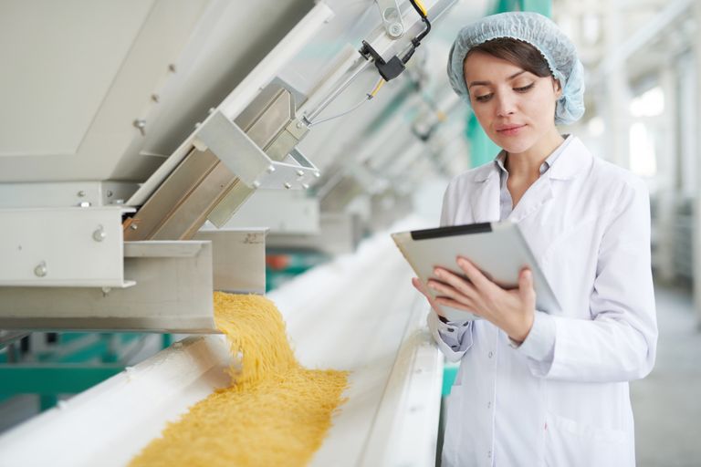 Quality inspector using a tablet to monitor pasta production on the shop floor